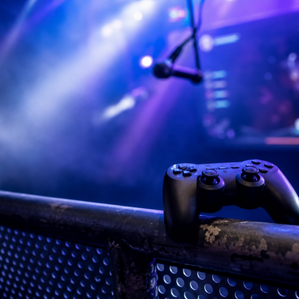 Palco com luzes coloridas, joystick e microfone sugerindo karaokê dentro de jogo, sem marcas visíveis.