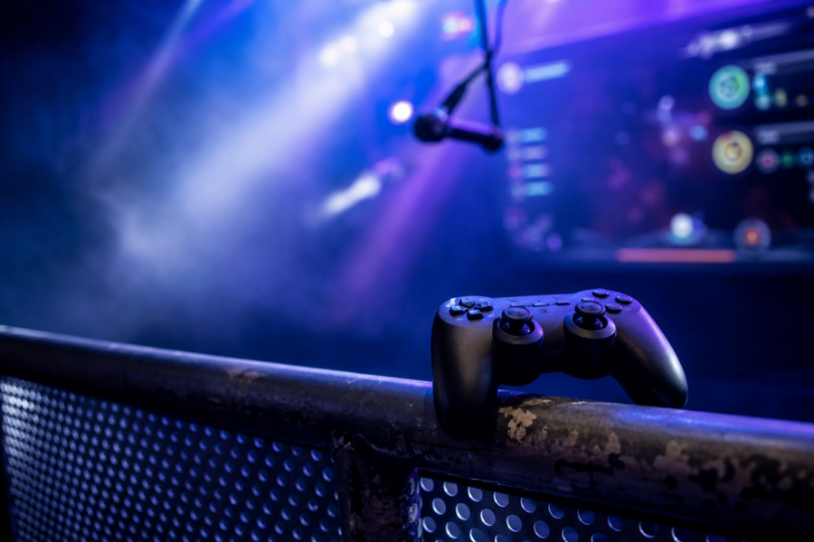 Palco com luzes coloridas, joystick e microfone sugerindo karaokê dentro de jogo, sem marcas visíveis.